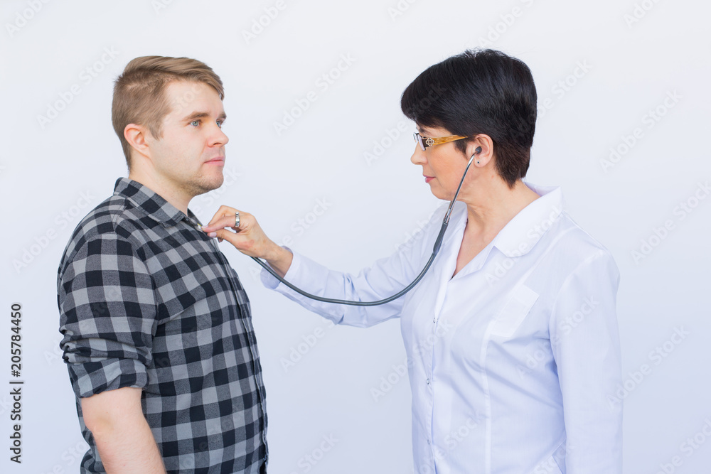 healthcare, medical exam, people and medicine concept - young man and doctor with stethoscope listening to heartbeat over white background healthcare, medical exam, people and medicine concept - young man and doctor with stethoscope listening to heartbeat over white background