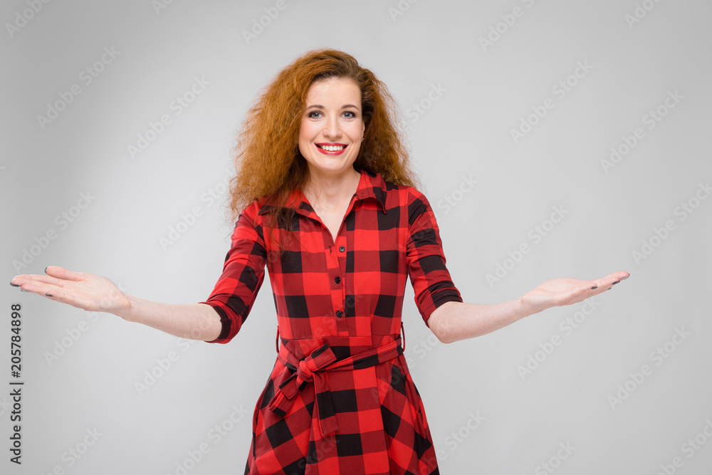 Young red-haired girl in a red checkered shirt. Young girl spread her arms Young red-haired girl in a red checkered shirt. Young girl spread her arms