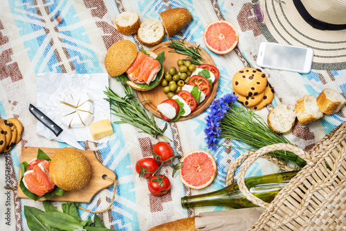 Fototapeta Naklejka Na Ścianę i Meble -  Picnic setting on the grass with basket, sandwiches, fruit, strawberry, salad and olives