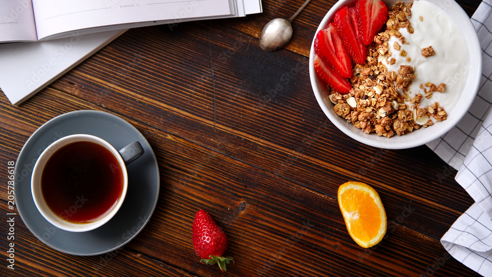Perfect breakfast: crunchy granola with yoghurt and strawberries with a cup of black coffee on wooden table. Flat lay with copy space Perfect breakfast: crunchy granola with yoghurt and strawberries with a cup of black coffee on wooden table. Flat lay with copy space