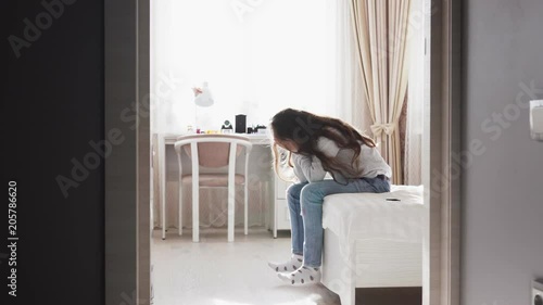 Sad child sitting on bed close her face with hands