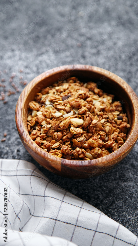 Granola in wooden bowl on gray background. Flatlay with copy space Granola in wooden bowl on gray background. Flatlay with copy space