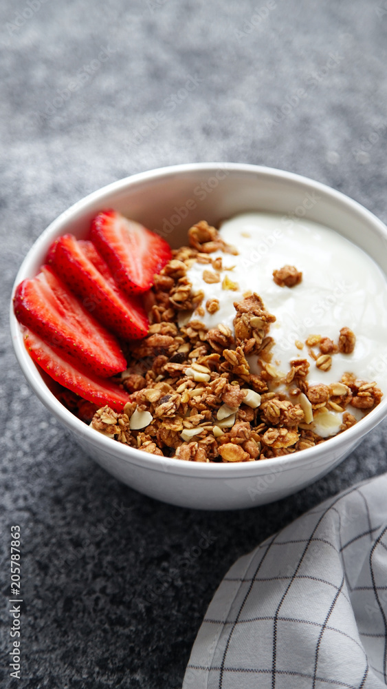 Close up shot of perfect breakfast: crunchy granola with yoghurt and strawberries with a cup of black coffee on gray bakcground. Close up shot of perfect breakfast: crunchy granola with yoghurt and strawberries with a cup of black coffee on gray bakcground.