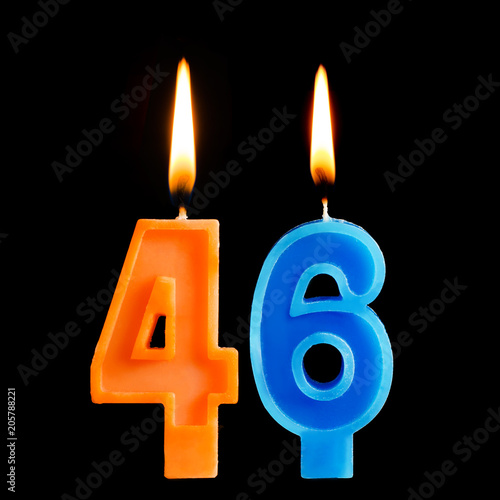 Burning birthday candles in the form of 46 forty six for cake isolated on black background. photo