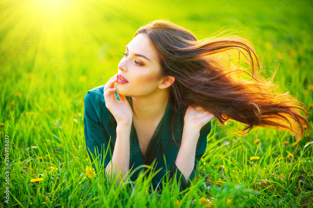 Beauty woman lying on the field enjoying nature. Beautiful brunette girl with healthy long flying hair. Summer green grass Beauty woman lying on the field enjoying nature. Beautiful brunette girl with healthy long flying hair. Summer green grass