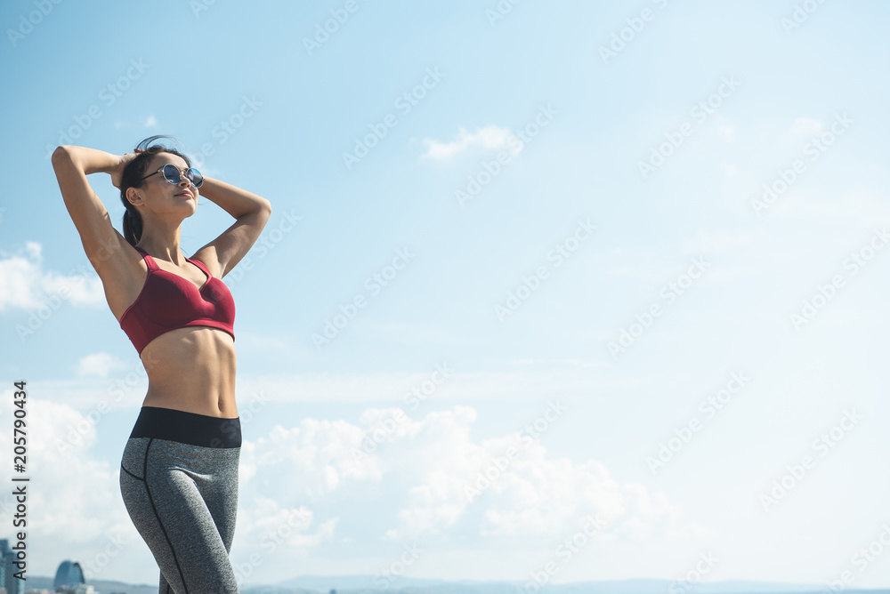 Portrait of smiling lady resting against blue sky after working out. Happy girl practicing gymnastic exercise concept Portrait of smiling lady resting against blue sky after working out. Happy girl practicing gymnastic exercise concept