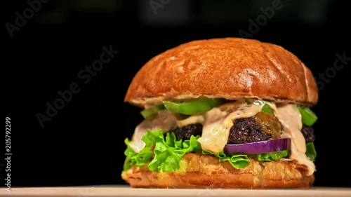 Cool beautiful fresh juicy cooked burger rotate on turntable. Very luscious air bun and marbled beef. Restaurant where each burgers is cooked by hand. Not made ideal. Not conveyor. Looks real, loving