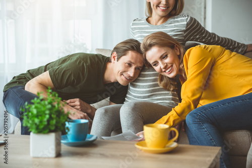 This is the real happiness. Portrait of glad married couple listening to female pregnant belly and smiling. They are looking at ultrasound picture with love. Surrogate motherhood concept 