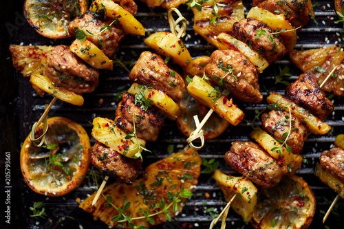 Grilled skewers with pineapple  and chicken meat  with herbs on a grill plate. Fruit and meat skewers, bbq, top view.