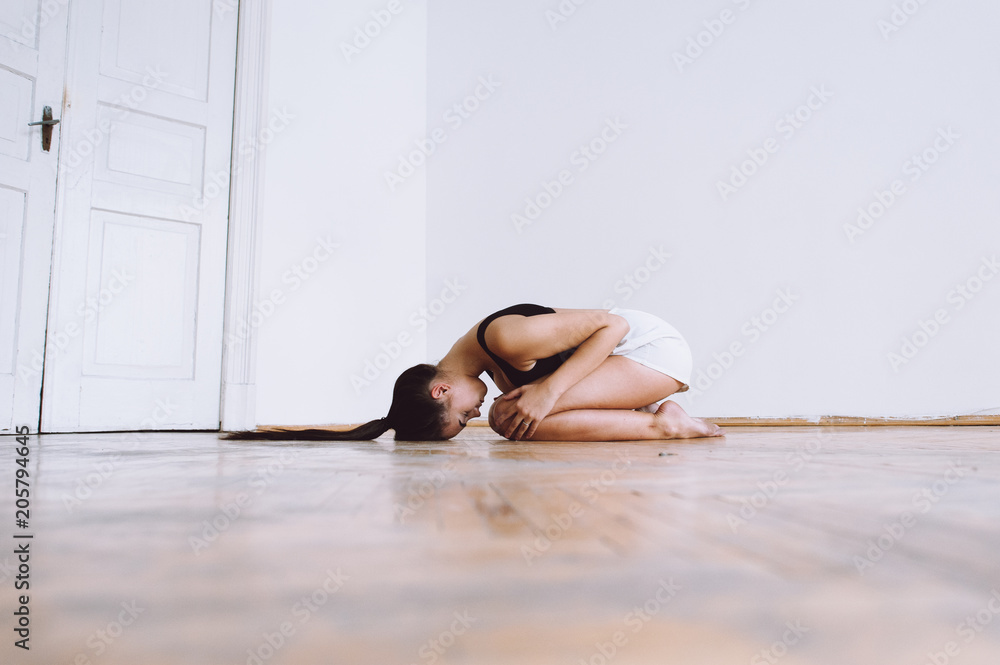 beautiful girl on a lacquered parquet in the middle of a white room under gravity problems