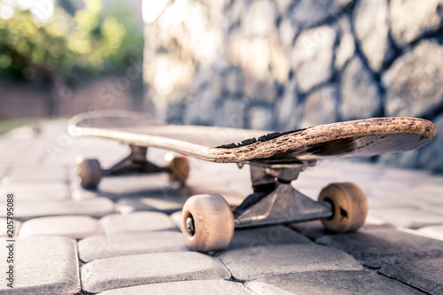 old skateboard close-up, against a background of paving slabs