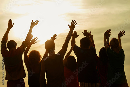 People putting hands up. Evening silhouette of kids raising hands up. photo