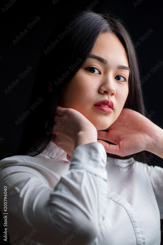 Portrait of beautiful long haired Asian woman in white shirt looking at ...
