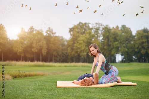 Thai massage elbow stretching. Mature woman getting masssage from young woman outdoor in the park. photo