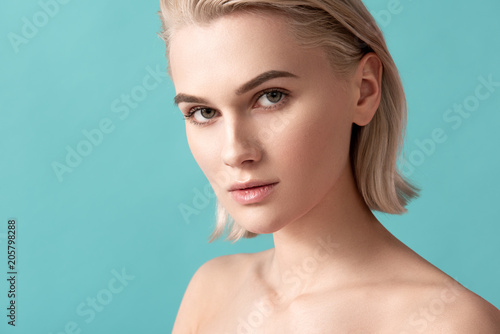 Beauty concept. Portrait of undressed tranquil woman with silky pelt looking at camera. Isolated on blue background photo