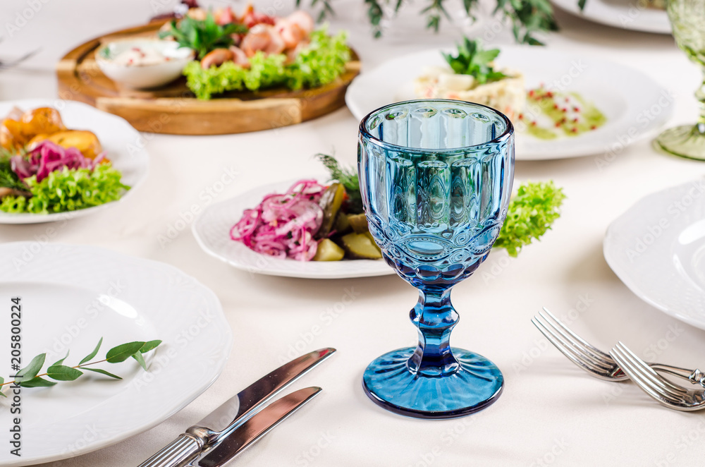 Empty blue glass on white tablecloth in a restaurant banquet, background with snacks and glasses of wine, close up. Concept: Furshet. Serving. Celebration. Anniversary. Wedding Empty blue glass on white tablecloth in a restaurant banquet, background with snacks and glasses of wine, close up. Concept: Furshet. Serving. Celebration. Anniversary. Wedding