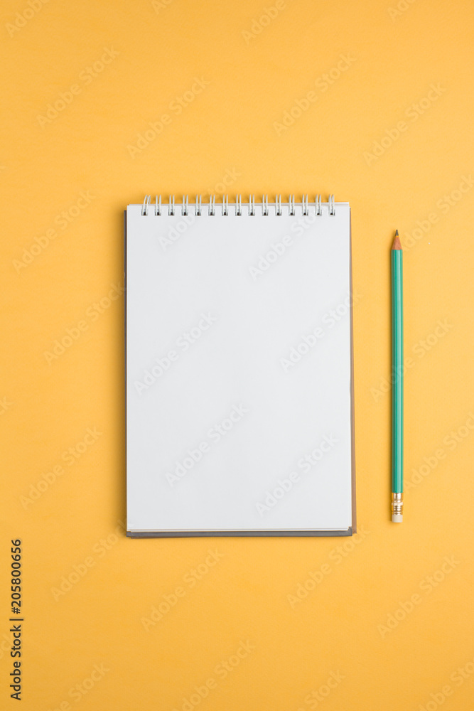 Blank notebook with pencil on yellow pastel background. Flat lay concept. Vertical orientation Blank notebook with pencil on yellow pastel background. Flat lay concept. Vertical orientation
