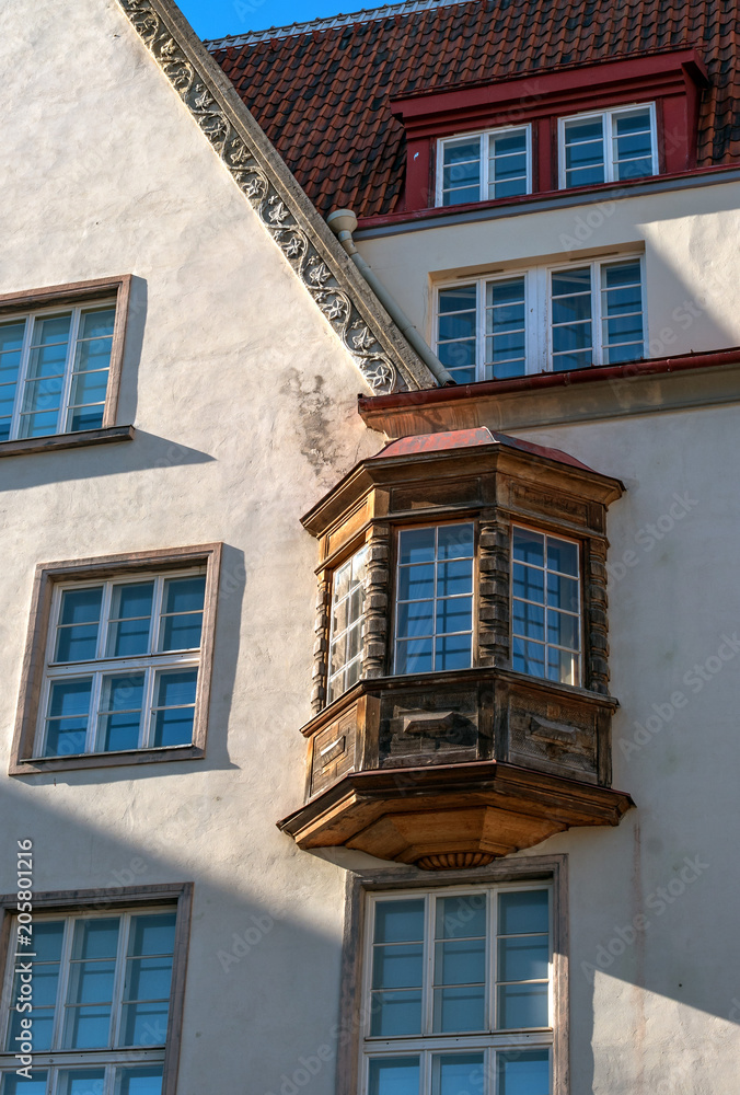 Bay window on the facade of a medieval house in Tallinn. Estonia. The Bay window is made of wood, the house is stone. The roof of the house is lined with clay tiles