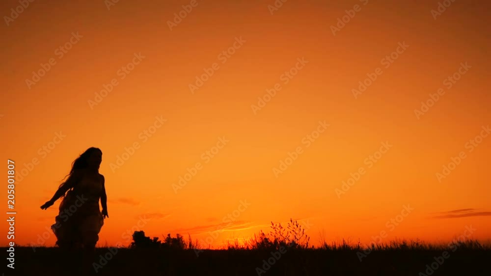 Silhouette of young girl jumping against orange sky Silhouette of young girl jumping against orange sky