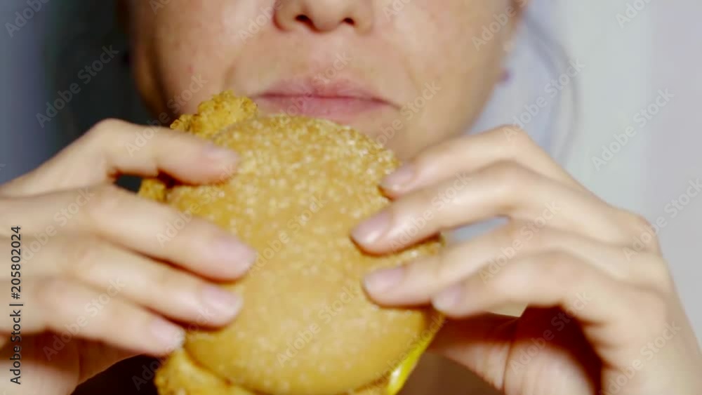 Close up shot of a woman bitting a piece of hamburger. Close up shot of a woman bitting a piece of hamburger.