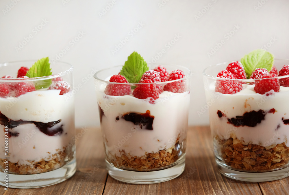 Healthy breakfast - yogurt with fresh berries and muesli served in glass jar, on wooden background Healthy breakfast - yogurt with fresh berries and muesli served in glass jar, on wooden background