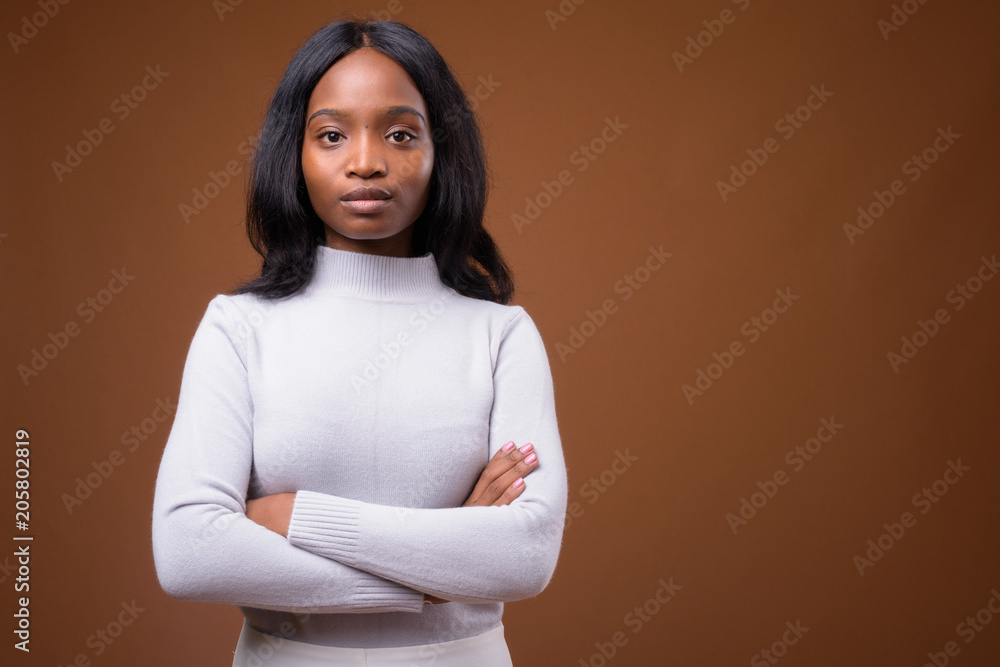 Fototapeta premium Young beautiful African Zulu businesswoman against brown backgro