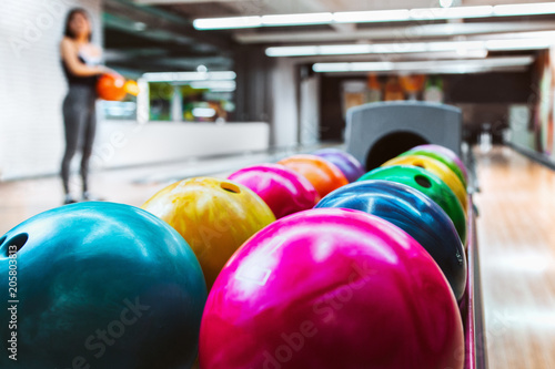 Rack Of Colorful Balls At A Bowling Alley with blurred player in background