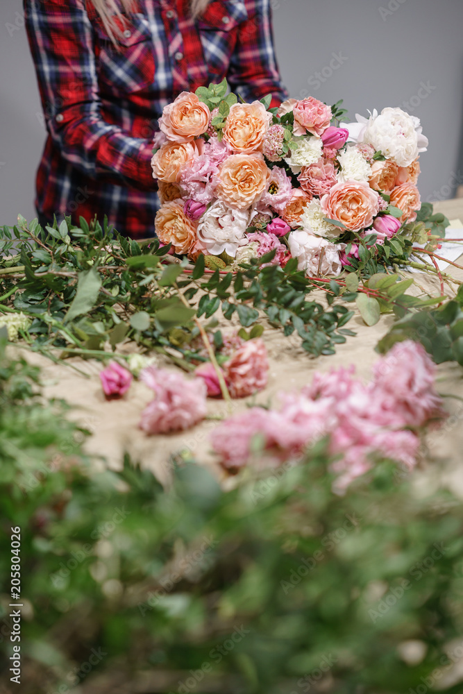 Female florist. Floral workshop - woman making a beautiful flower composition a bouquet. Floristry concept