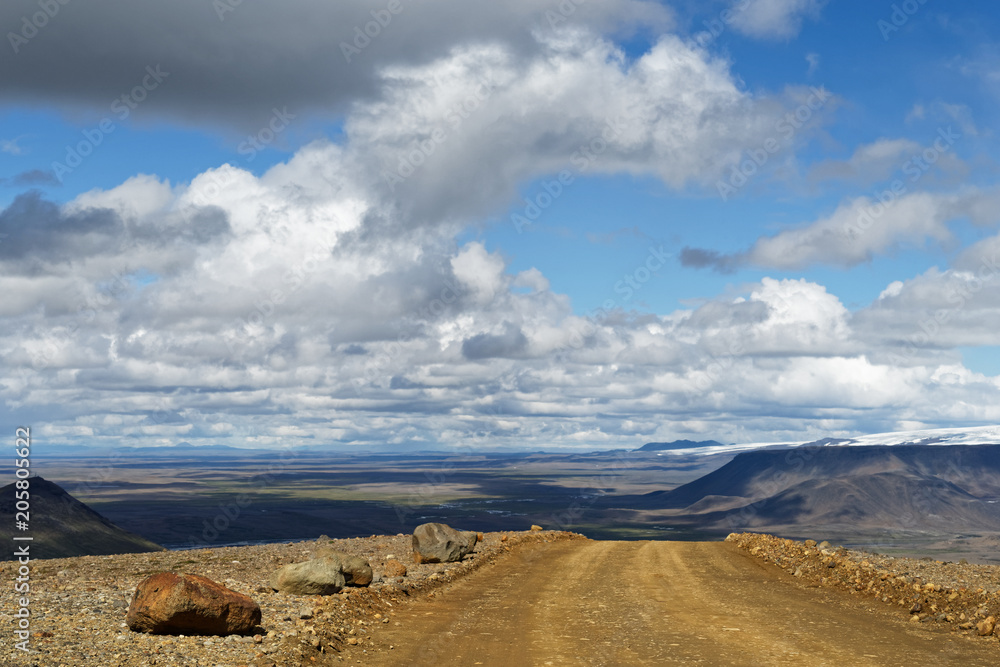 Small Hill Ranges A gravel road leads over a small hill, behind it is a wide landscape ...
