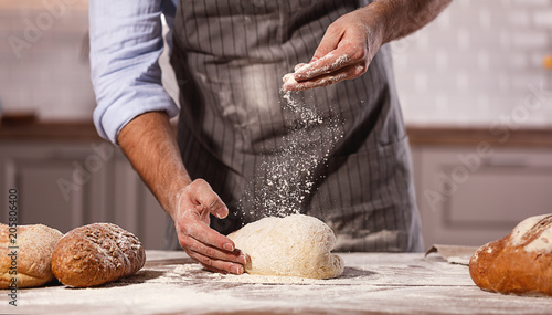 hands of baker's male knead dough.