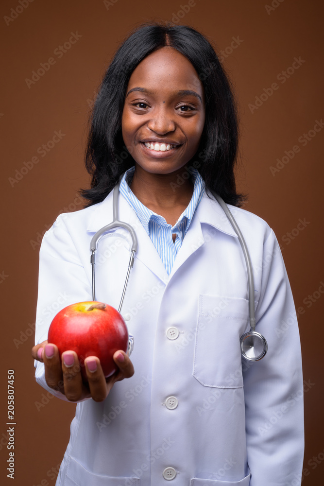 Young beautiful African Zulu woman doctor against brown backgrou Young beautiful African Zulu woman doctor against brown backgrou