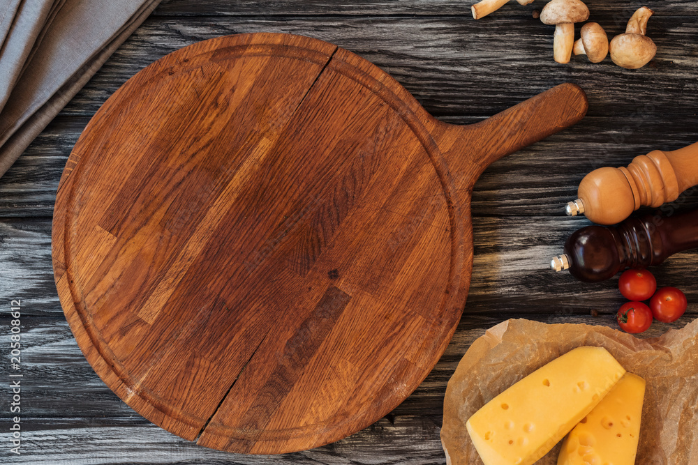 top view of empty wooden cutting board, spices, cheese and vegetables on table top view of empty wooden cutting board, spices, cheese and vegetables on table