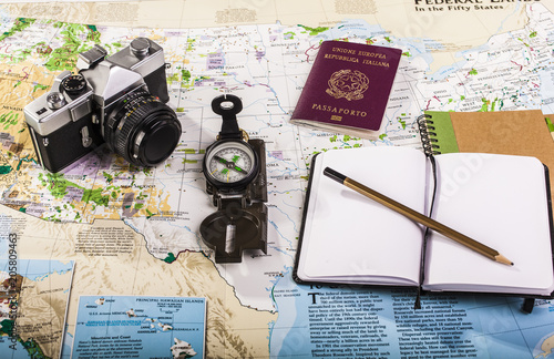 Compass, passport, photo camera and block notes on map