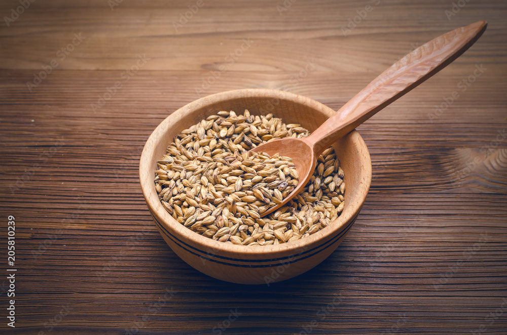 Malt in wooden bowl with spoon on brown wooden table background. Malt in wooden bowl with spoon on brown wooden table background.