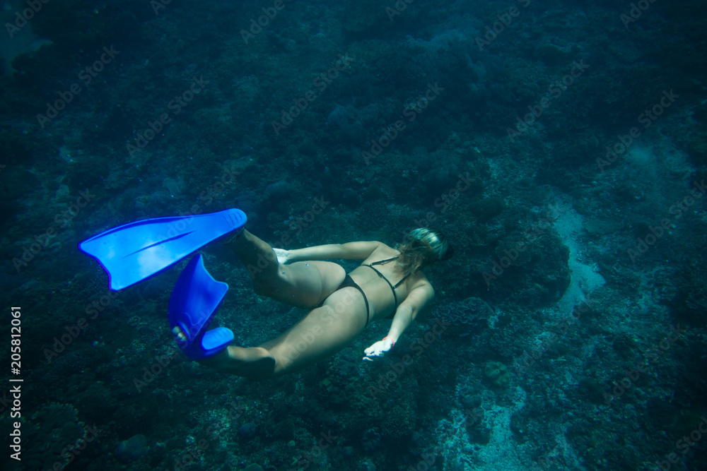 back view of woman in bikini and fins diving in ocean alone