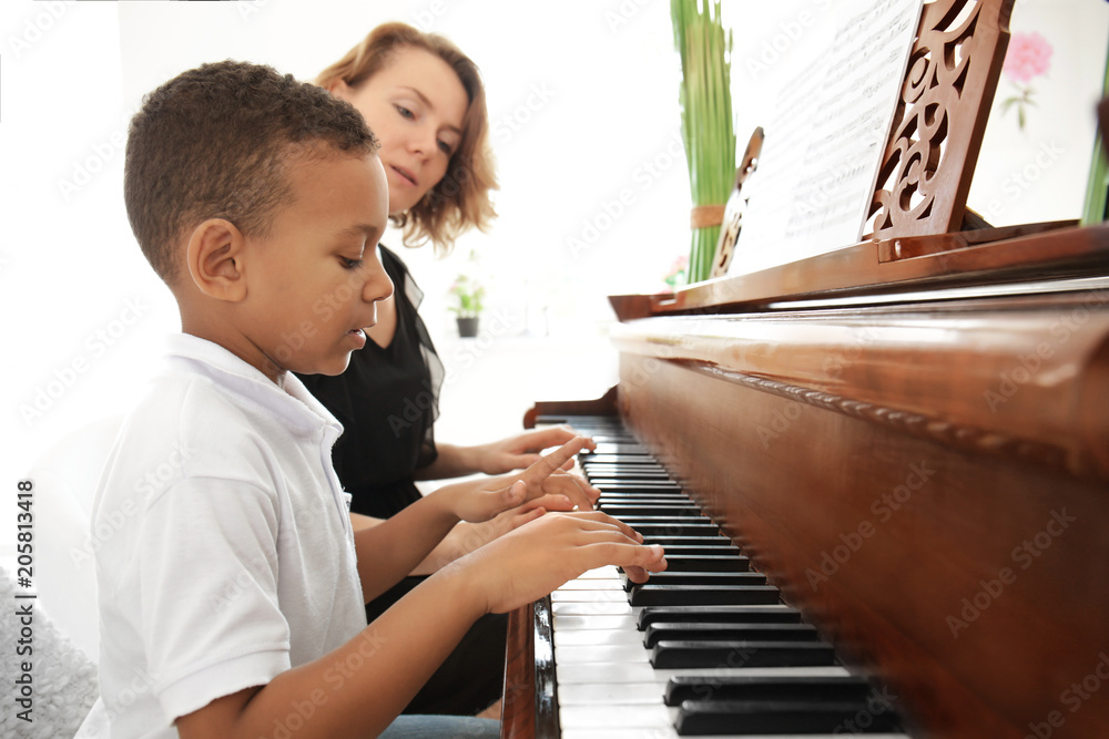 African-American boy with teacher learning to play piano indoors Stock  Photo | Adobe Stock