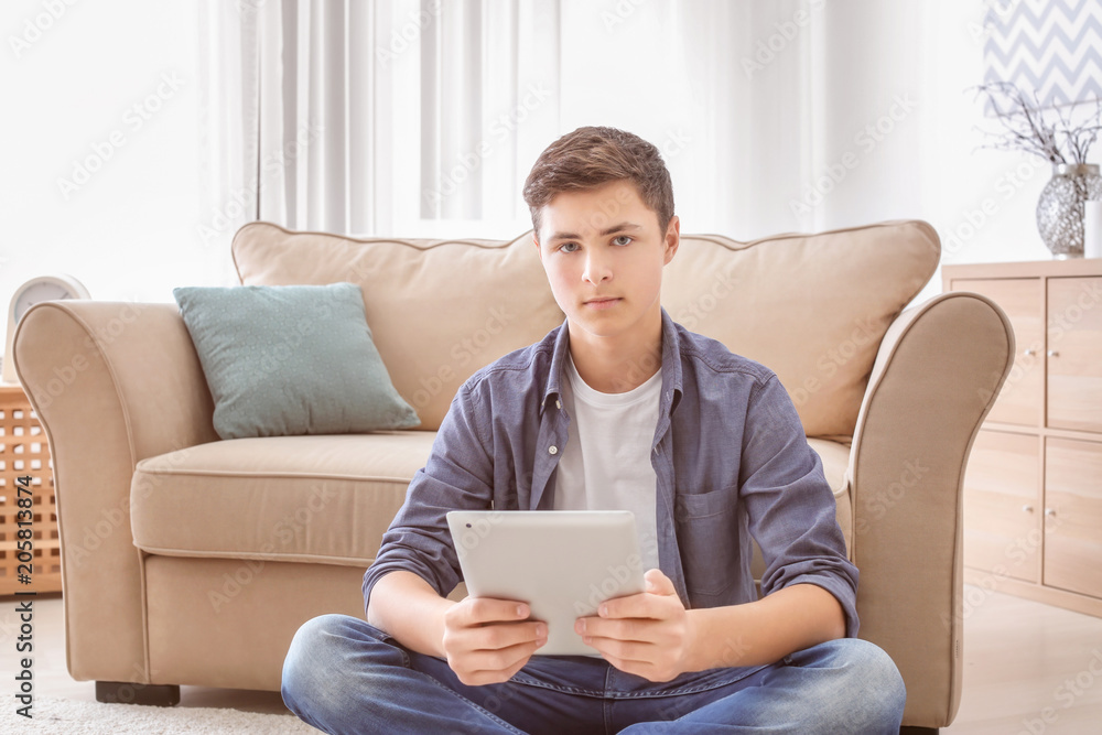 Stylish teenager using tablet computer in room