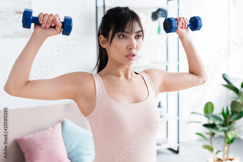 fit young woman working out with dumbbells at home