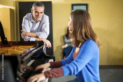 Two young women at a piano time with a teacher