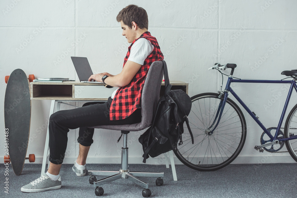 student using laptop at table with skateboard and bicycle near student using laptop at table with skateboard and bicycle near
