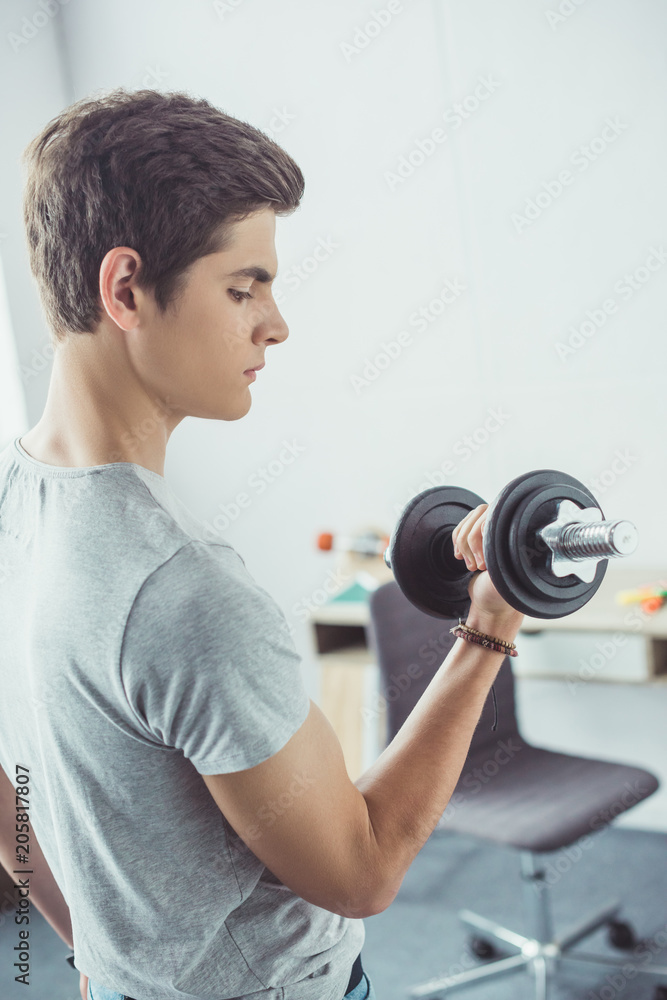 young teenager exercising with dumbbell at home young teenager exercising with dumbbell at home