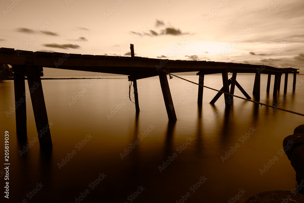 Wooden bridge in the evening sea using Long Exposure Photography technique to make vintage tone.