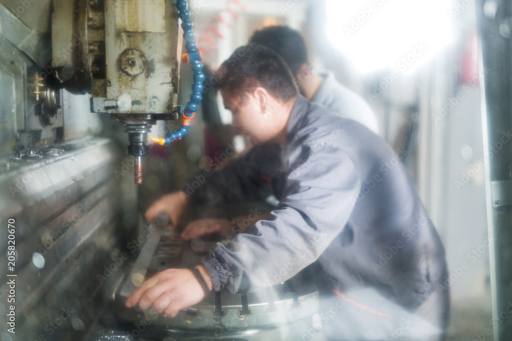 Metal workers working on CNC machine Metal workers working on CNC machine