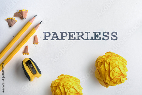 PAPERLESS text and Yellow pencil and a yellow crumpled paper with shaving on white drawing watercolor paper photo