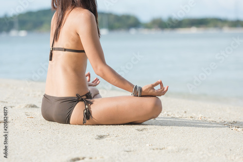 Young healthy woman practicing yoga on the beach