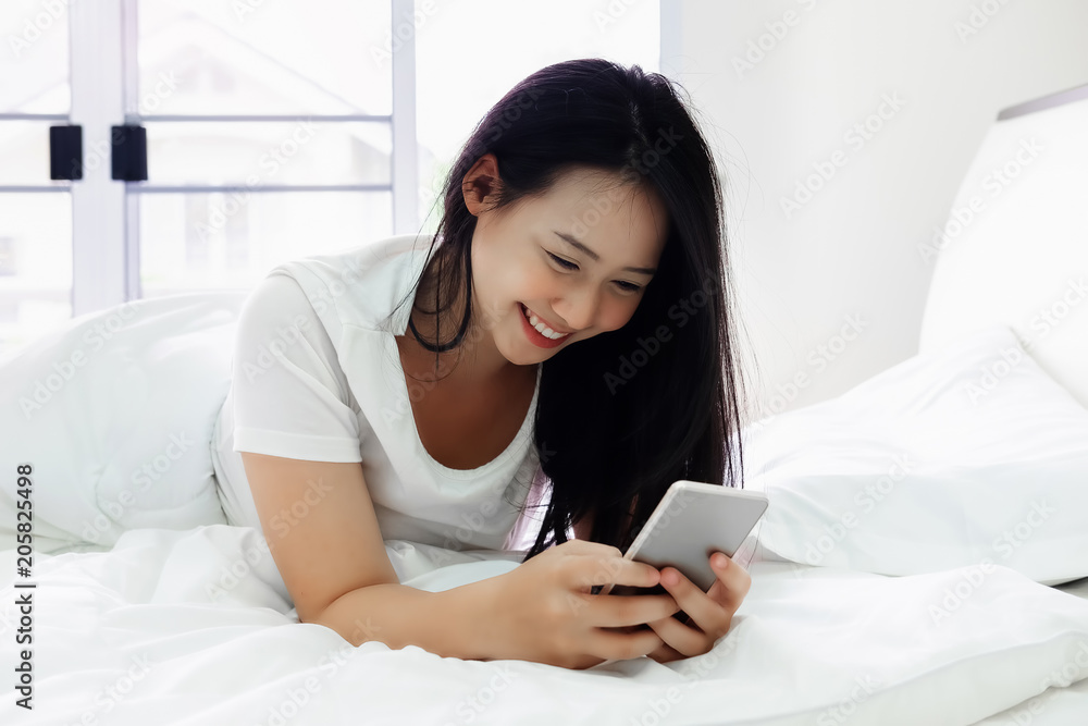 Cute girl using smartphone for online shopping or call phone on the bedroom in house. Cute girl using smartphone for online shopping or call phone on the bedroom in house.