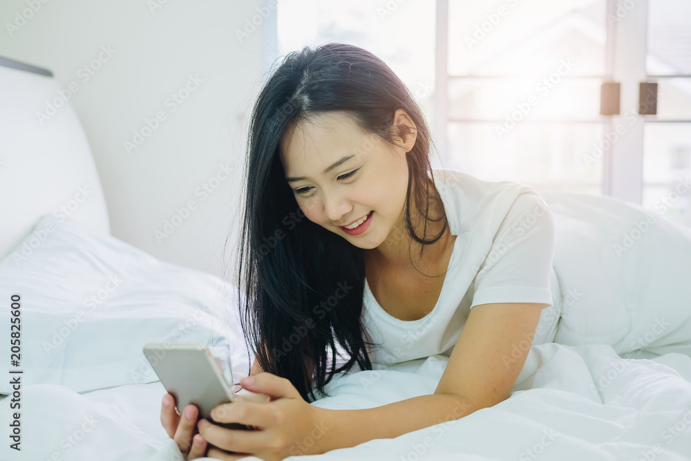 Cute girl using smartphone for online shopping or call phone on the bedroom in house. Cute girl using smartphone for online shopping or call phone on the bedroom in house.