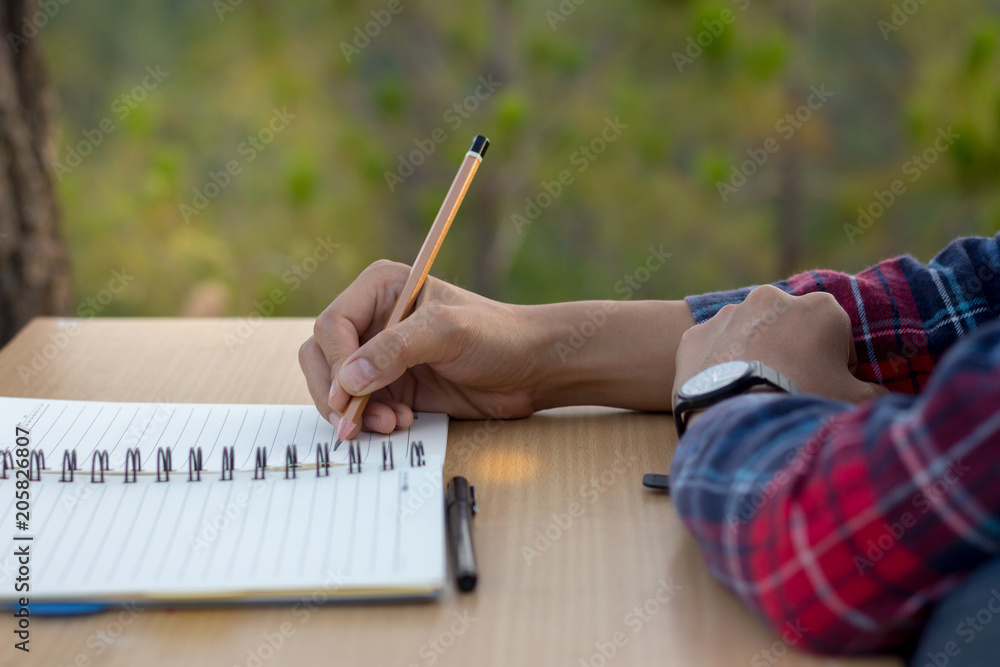 The girl sat down to write a notebook on a wooden table to plan a study.  Stock Photo | Adobe Stock