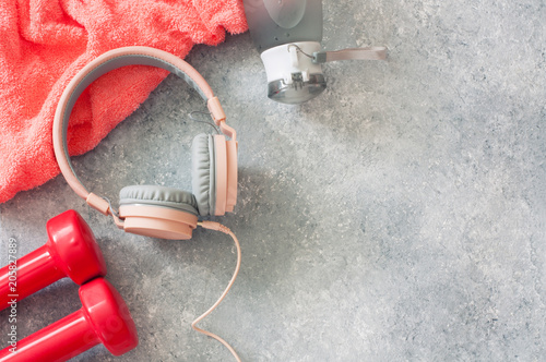 Fitness concept with dumbbells, headphones, towel and bottle of water