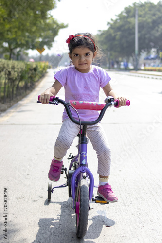 Fototapeta Naklejka Na Ścianę i Meble -  Little girl riding bicycle on the street